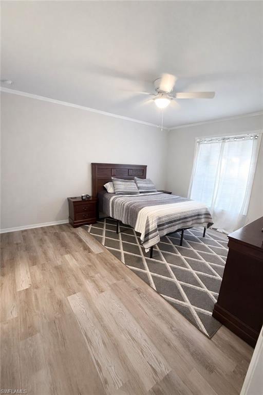 Bedroom featuring crown molding, light wood finished floors, and ceiling fan