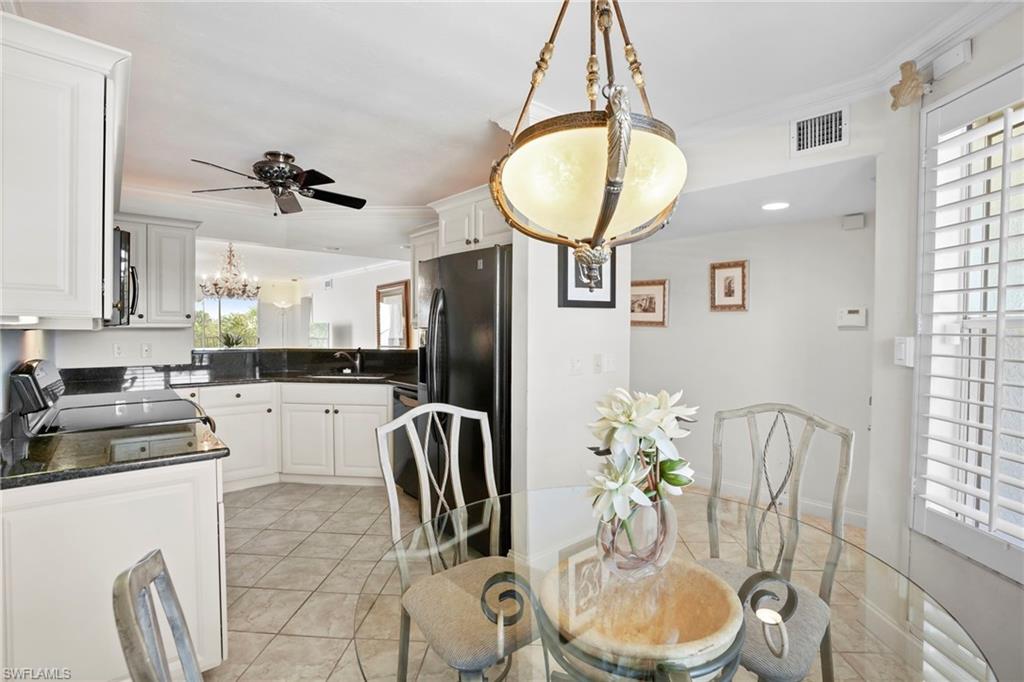 Dining area featuring a chandelier, a ceiling fan, light tile patterned floors, and crown molding