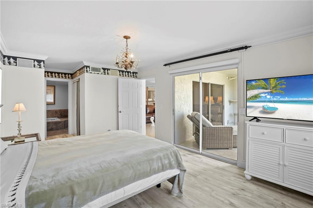 Bedroom with crown molding, access to exterior, light wood-style floors, and hanging lights