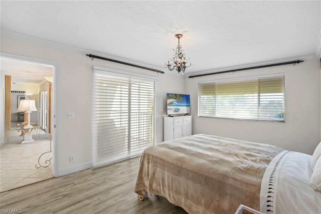 Bedroom with ornamental molding, light wood-style flooring, and suspended lighting