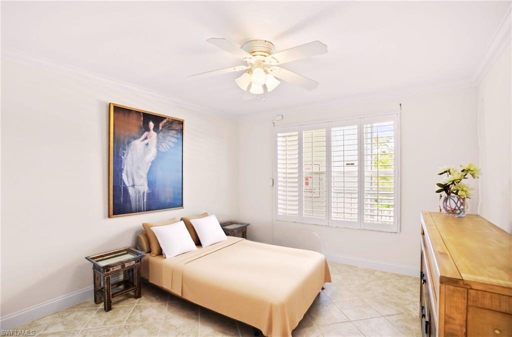 Guest-Bedroom partial staged with crown molding, a ceiling fan, and light tile patterned floors