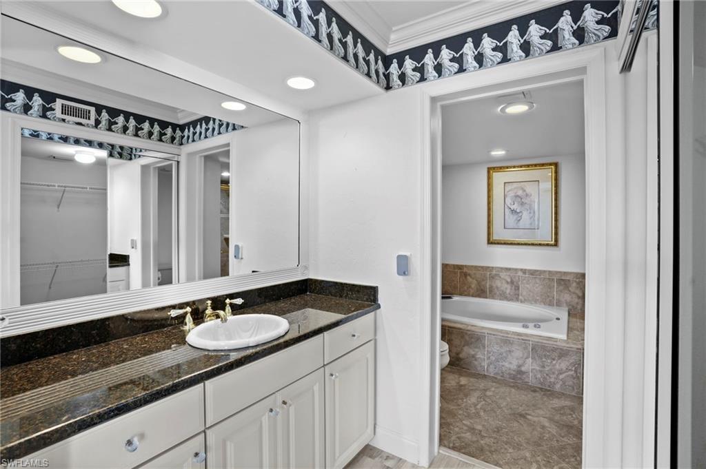 Full bathroom with recessed lighting, crown molding, vanity, a bath, and a walk in closet