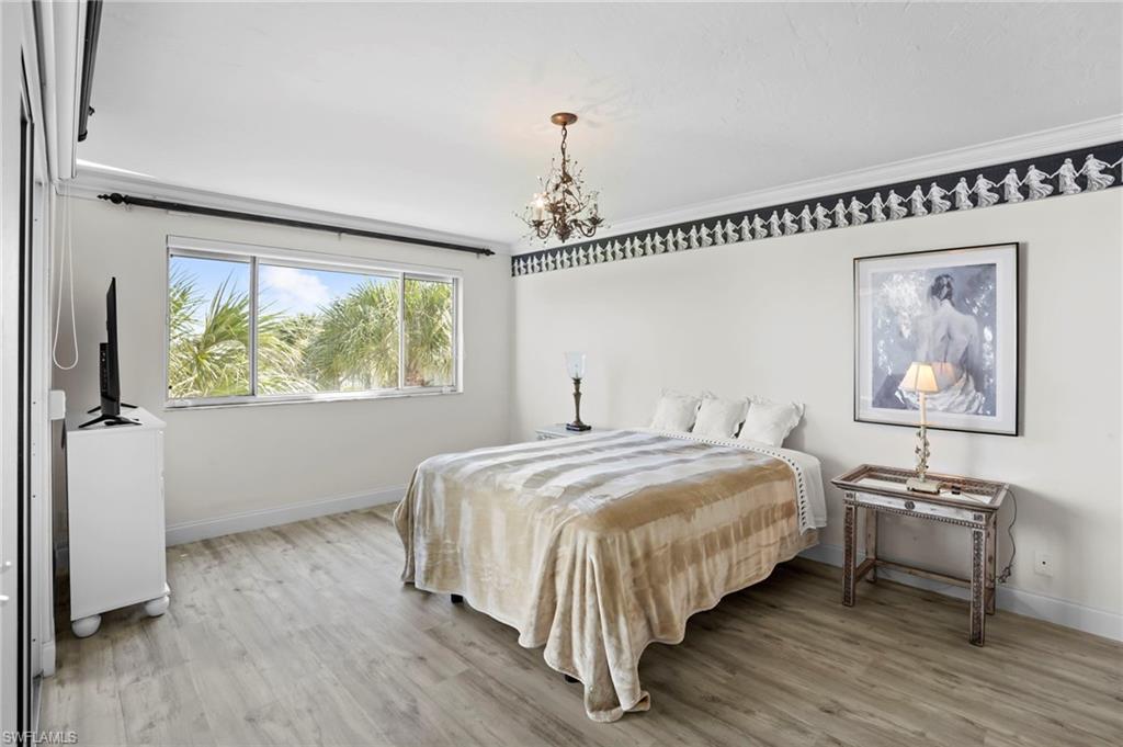 Bedroom with hanging lights, light wood-style flooring, and crown molding