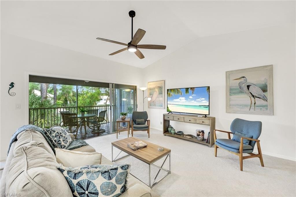 Living area with lofted ceiling, carpet flooring, and a ceiling fan