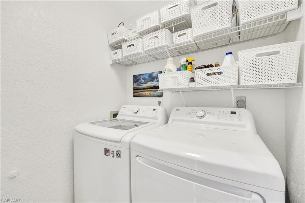 Laundry area featuring a textured wall and washing machine and dryer