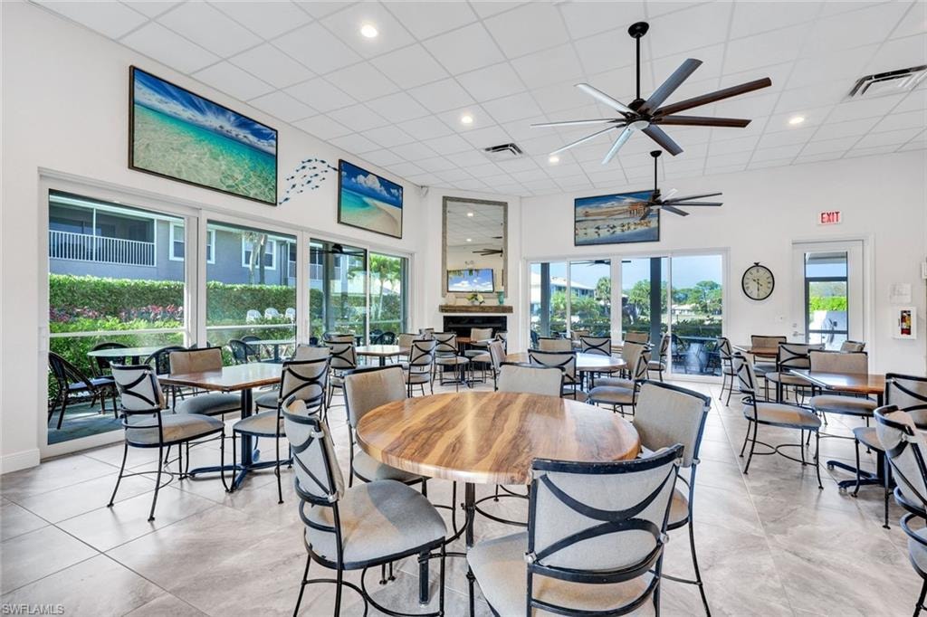 Dining room featuring ceiling fan, a high drop ceiling, and a fireplace