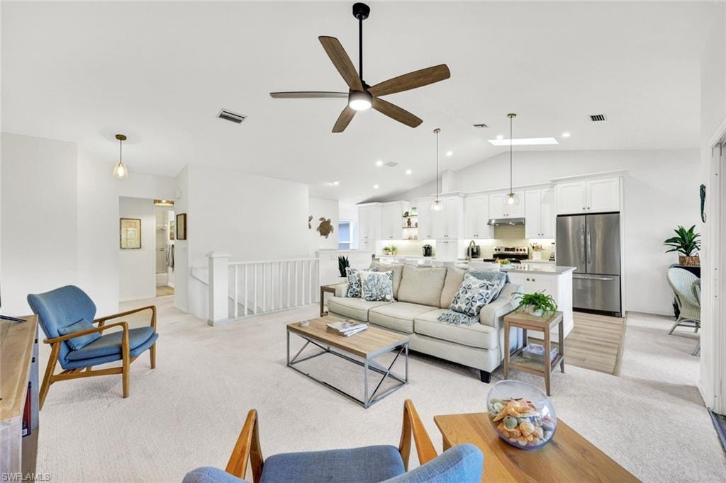 Living area featuring light colored carpet, a ceiling fan, and a high ceiling