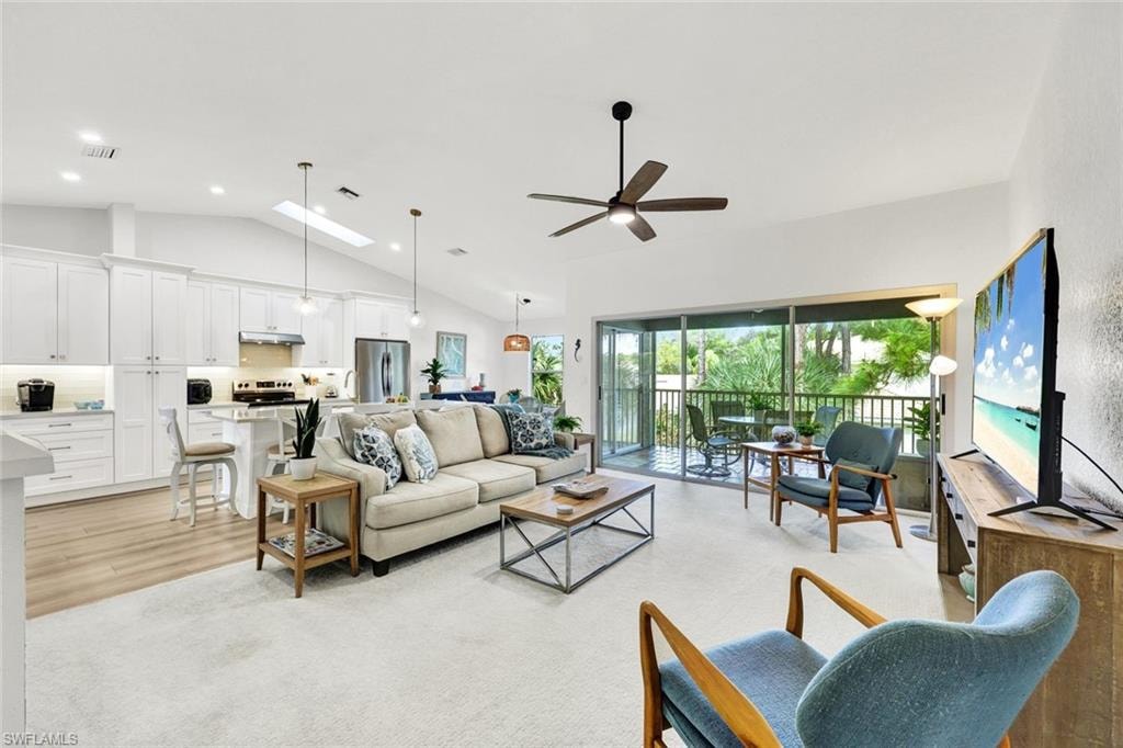 Living area featuring a skylight, ceiling fan, and vaulted ceiling