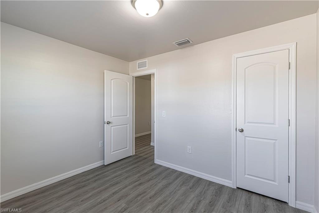 Unfurnished bedroom with baseboards and wood finished floors