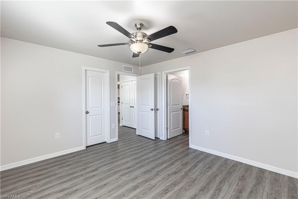 Unfurnished bedroom featuring wood finished floors, ceiling fan, and ensuite bath