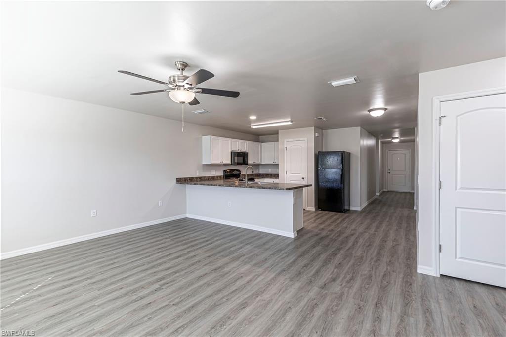 Kitchen featuring a peninsula, black appliances, white cabinets, open floor plan, and ceiling fan