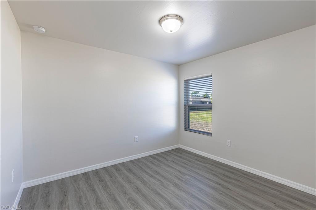 Unfurnished room featuring wood finished floors and baseboards