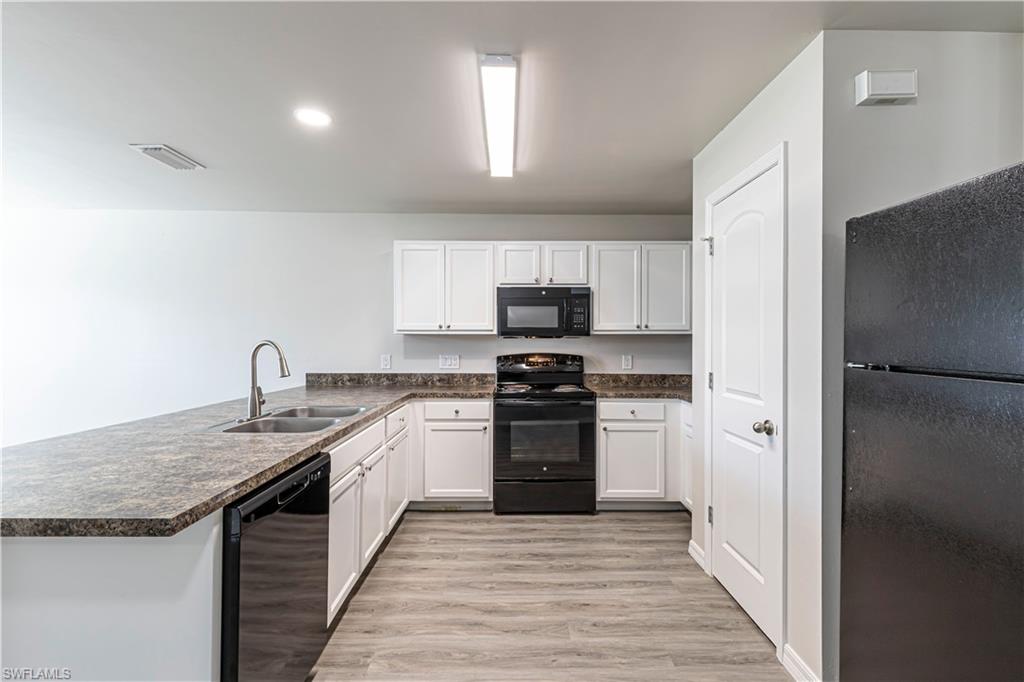 Kitchen with black appliances, white cabinetry, light wood-style flooring, a peninsula, and recessed lighting