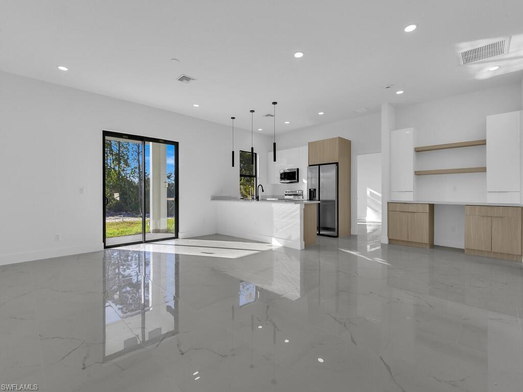 Unfurnished living room featuring light marble finish flooring and recessed lighting
