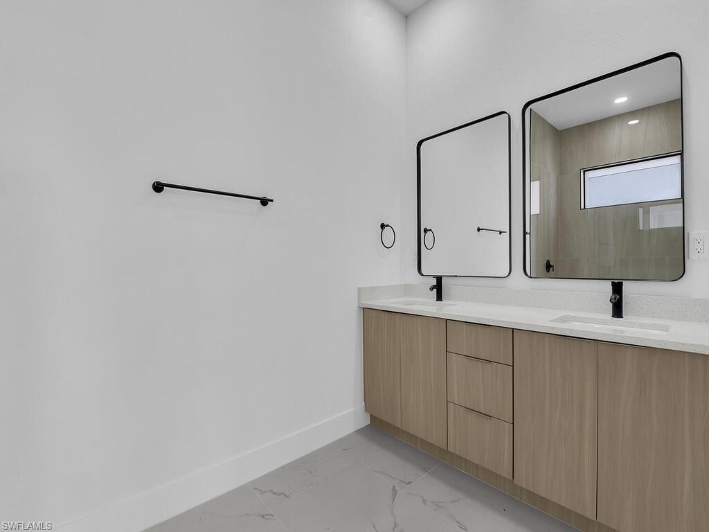 Bathroom featuring double vanity and light marble finish flooring
