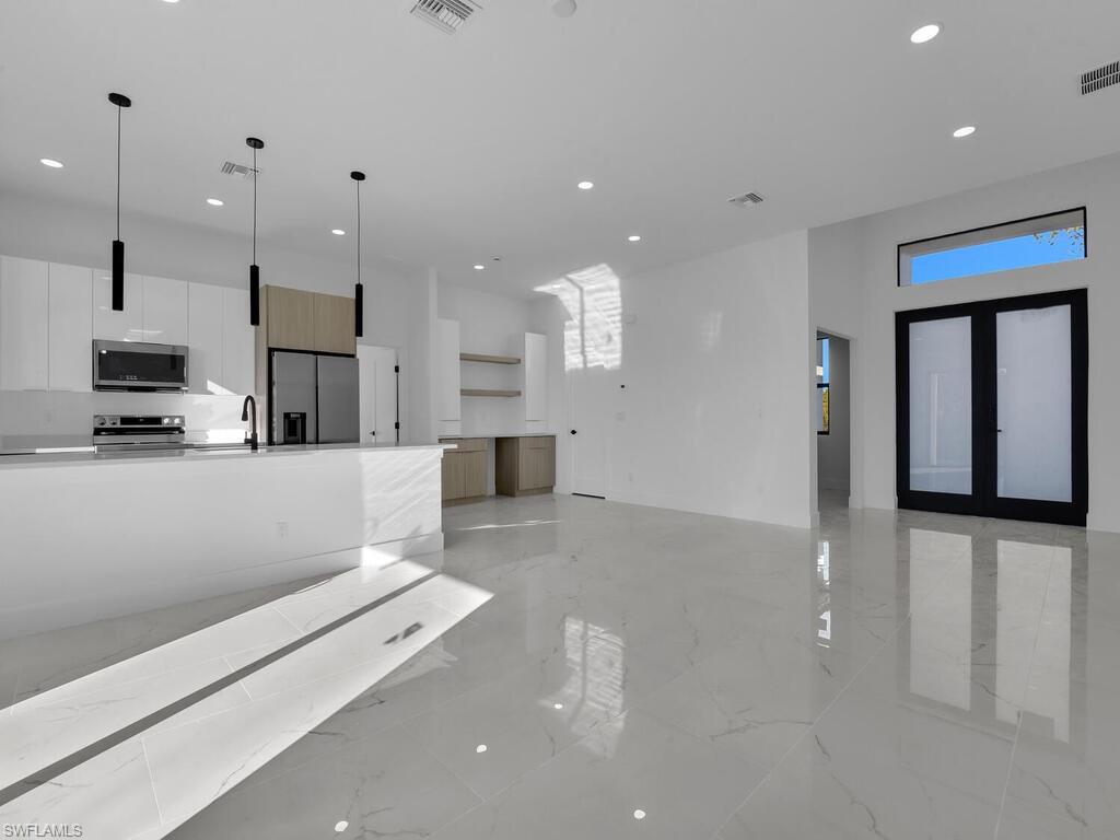 Two tone kitchen featuring open floor plan, modern cabinets, stainless steel appliances, two tone color scheme, and open shelves