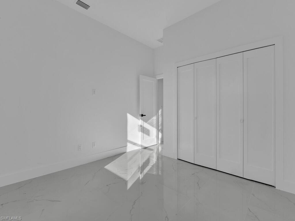 Unfurnished bedroom with light marble finish floors and a closet