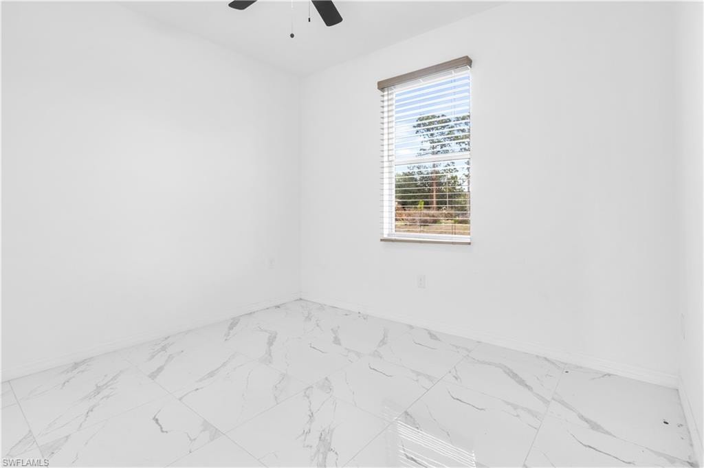 Empty room with marble look tile flooring and ceiling fan