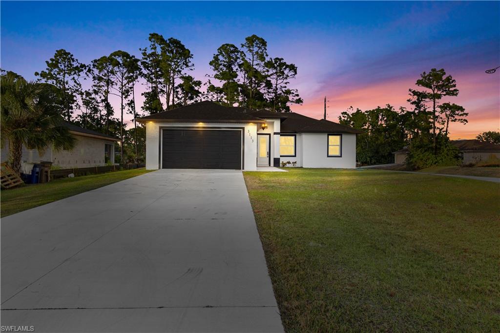 View of front of home with a front lawn, concrete driveway, an attached garage, and stucco siding