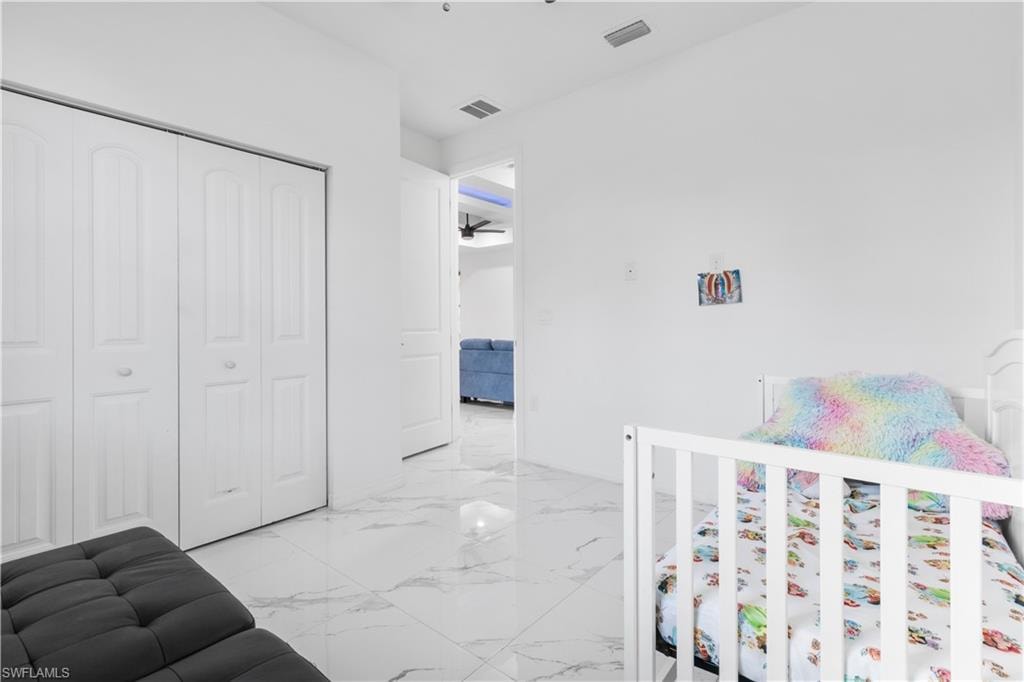 Bedroom featuring light marble finish flooring and a closet