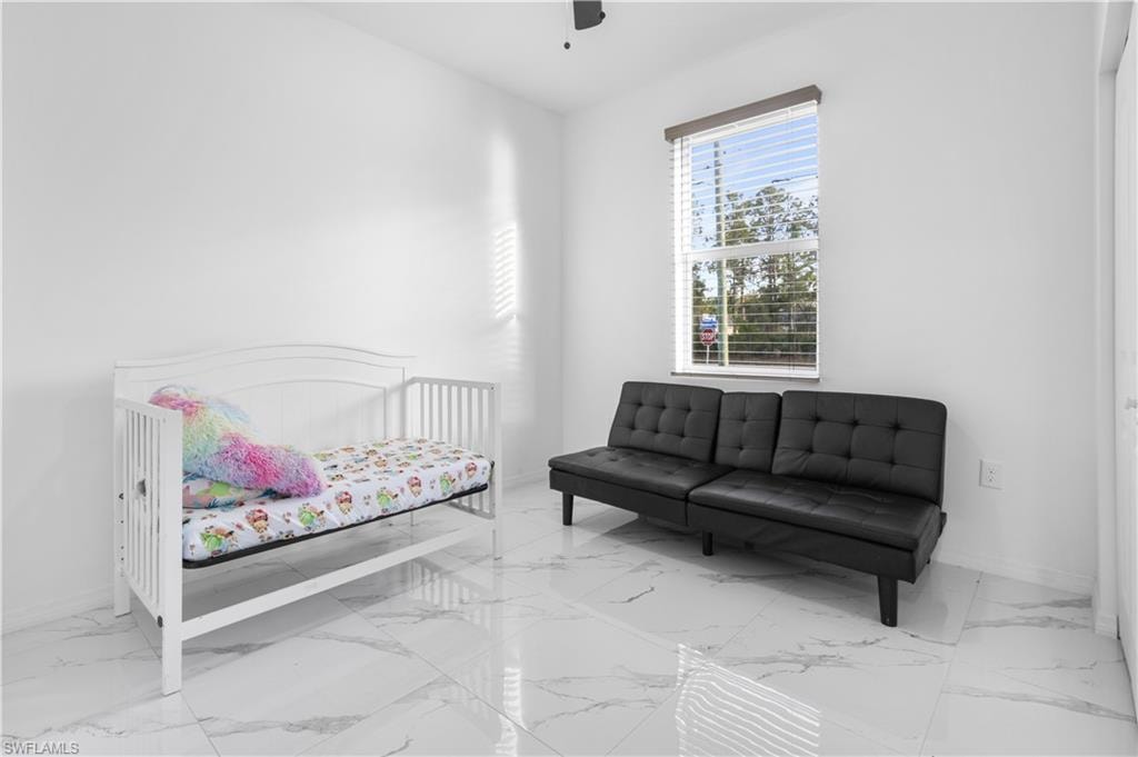 Bedroom with a ceiling fan and marble finish floors