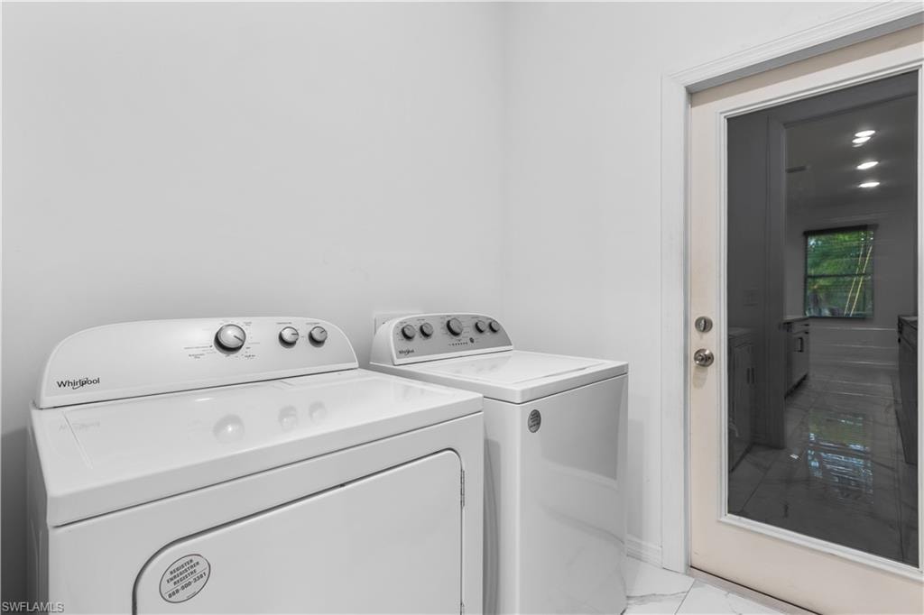 Laundry area featuring marble look tile flooring and washer and clothes dryer