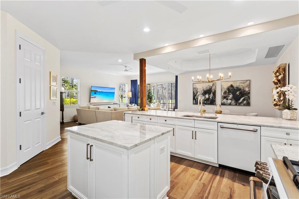 Kitchen featuring open floor plan, range, white dishwasher, light wood finished floors, and a raised ceiling