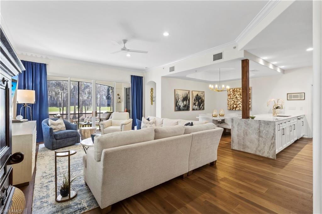 Living area featuring ornamental molding, dark wood finished floors, ceiling fan, and hanging lights
