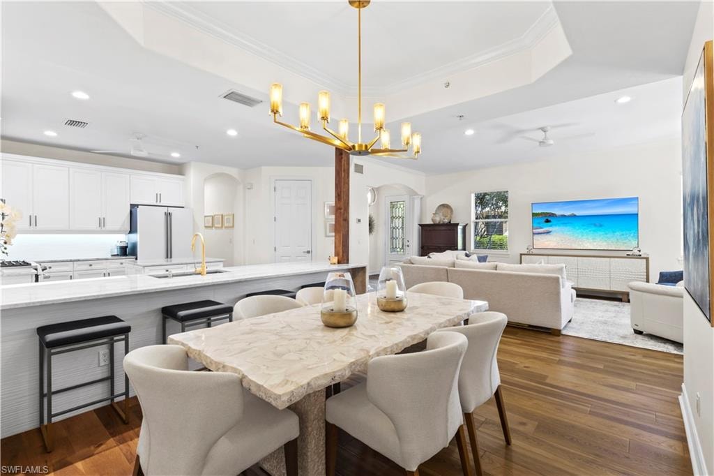 Dining area featuring a ceiling fan, arched walkways, dark wood-type flooring, hanging lights, and ornamental molding