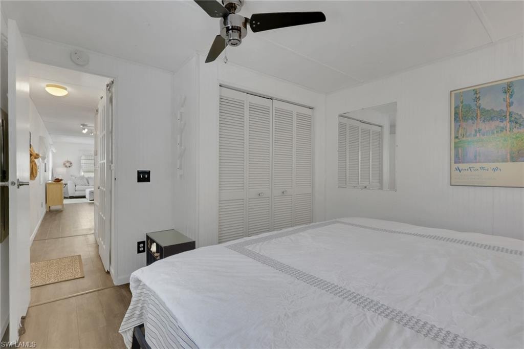 Bedroom with a closet, ceiling fan, and light wood-style flooring