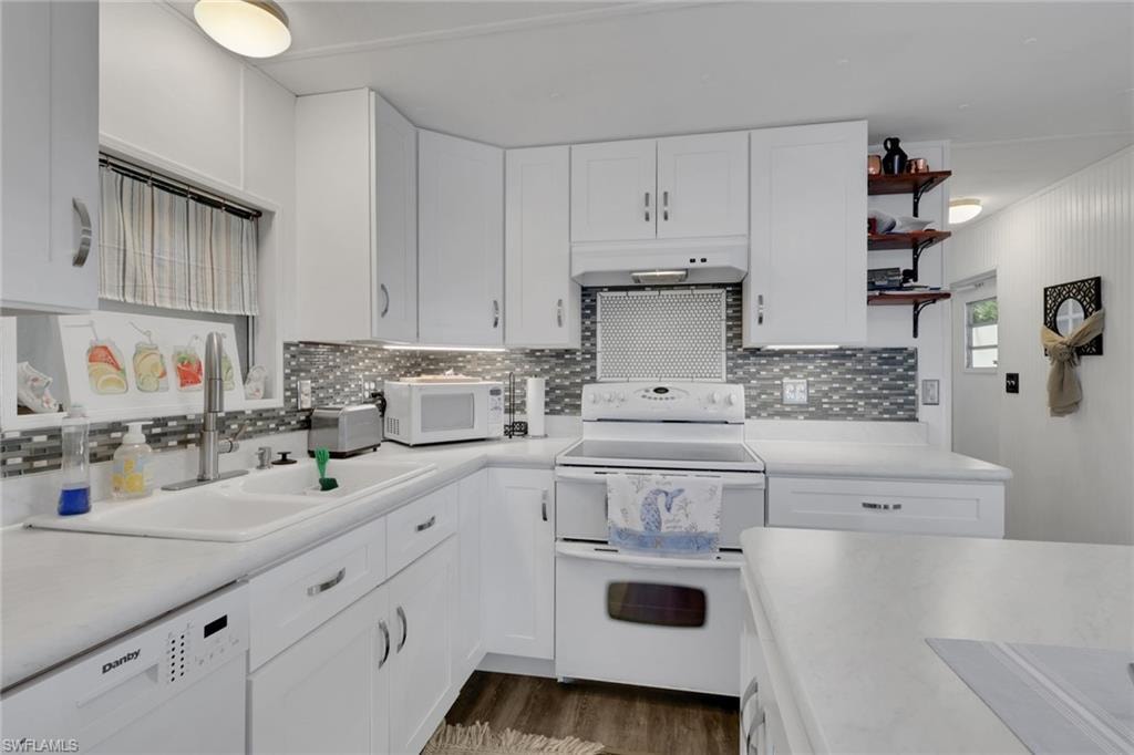 Kitchen featuring white appliances, white cabinets, light countertops, and open shelves