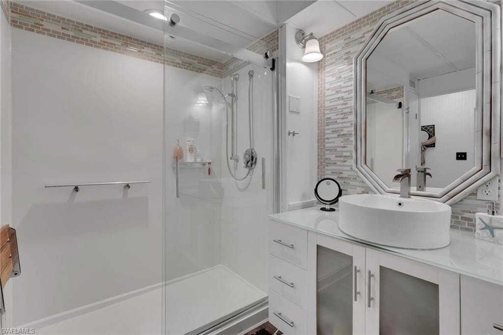 Bathroom with vanity, tasteful backsplash, and a stall shower