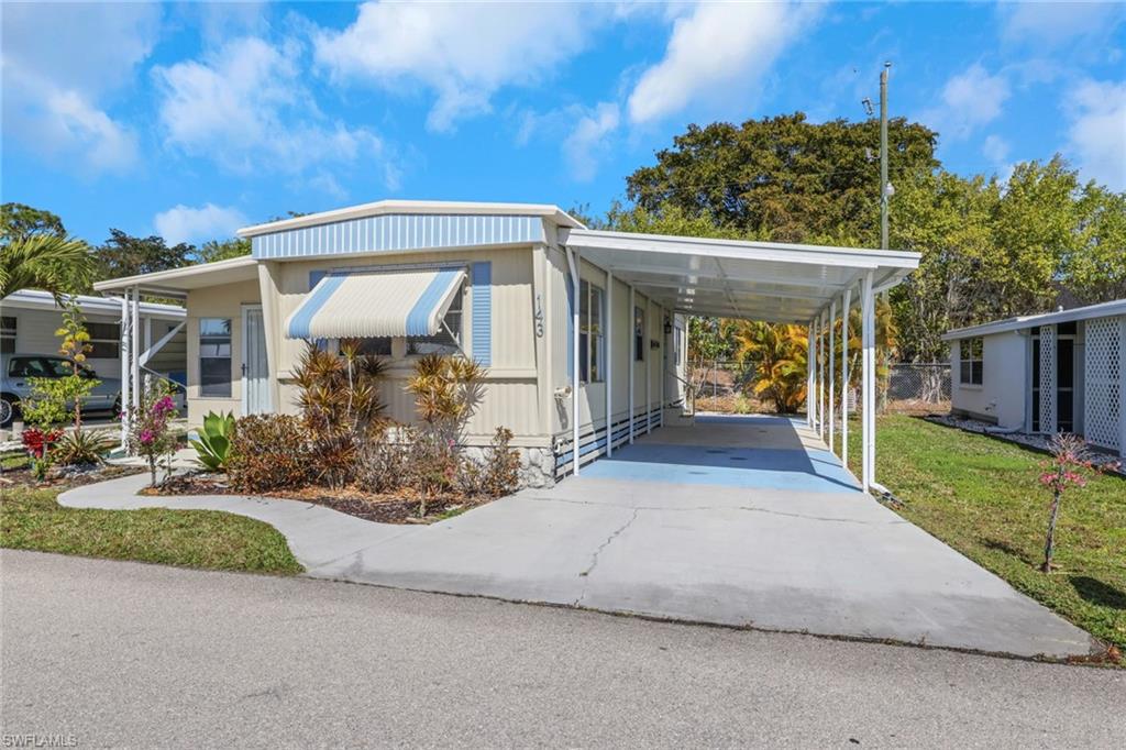Manufactured / mobile home featuring an attached carport, concrete driveway, and a front lawn