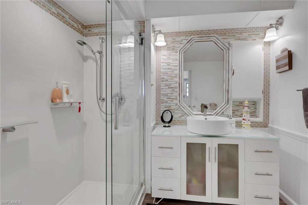 Full bath with vanity, a shower stall, wainscoting, and tasteful backsplash