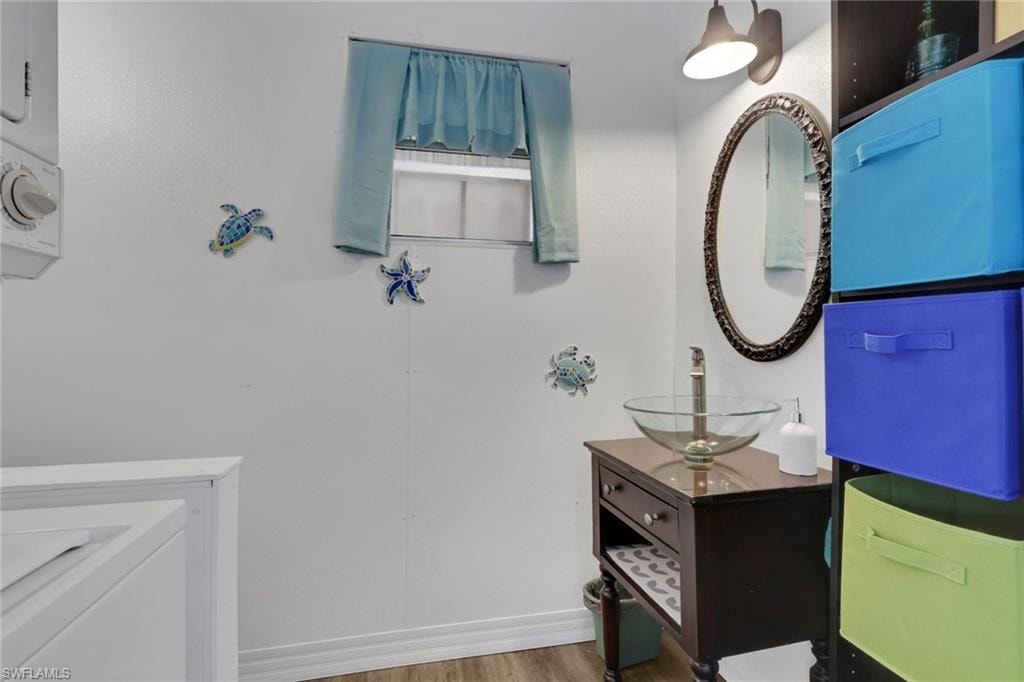 Bathroom with vanity, wood finished floors, and stacked washer / dryer