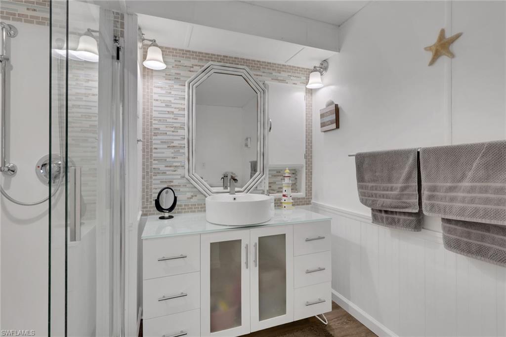 Full bathroom featuring vanity, wainscoting, a stall shower, and dark wood-type flooring