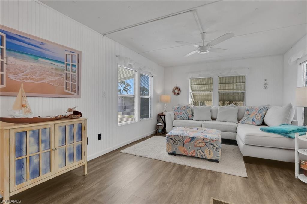 Living area featuring wood finished floors, a ceiling fan, and wood walls