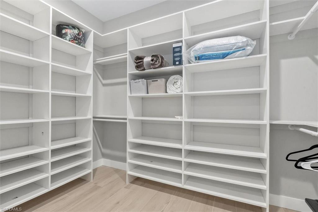 Walk in closet with light wood finished floors
