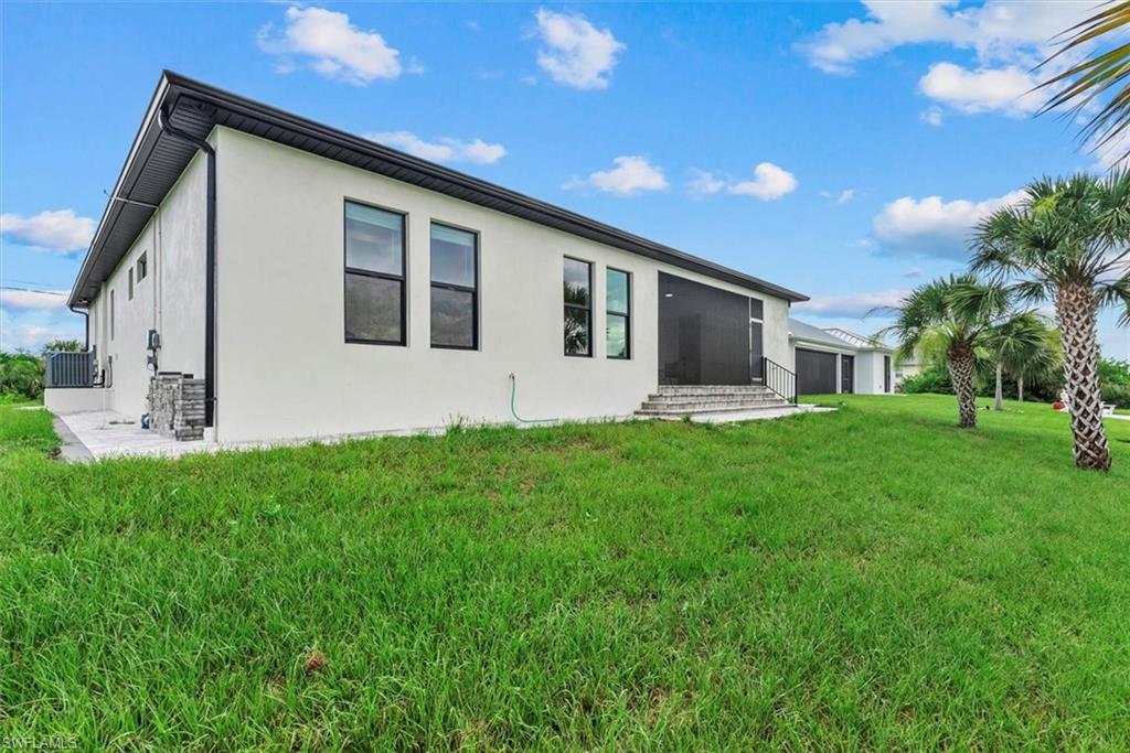 Rear view of house with a lawn and stucco siding