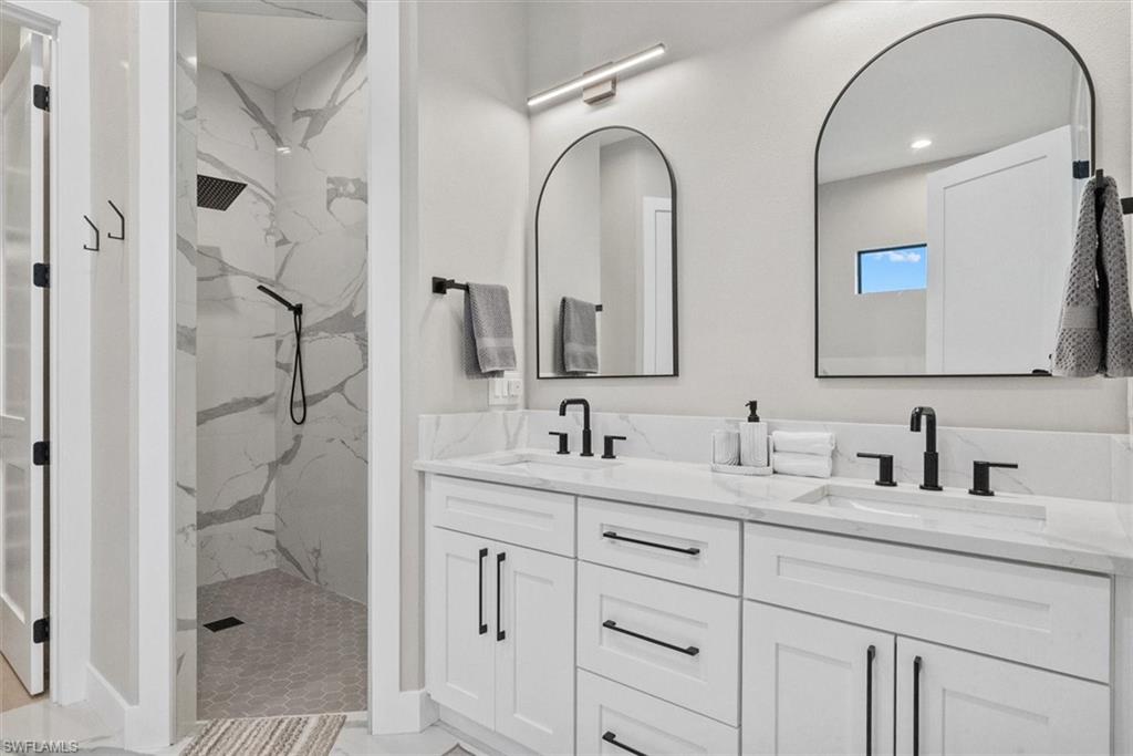 Full bath with double vanity, a marble finish shower, and recessed lighting