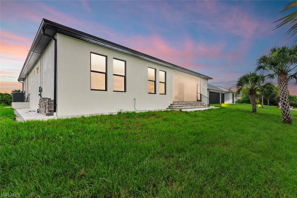 Back of house at dusk with a yard and stucco siding