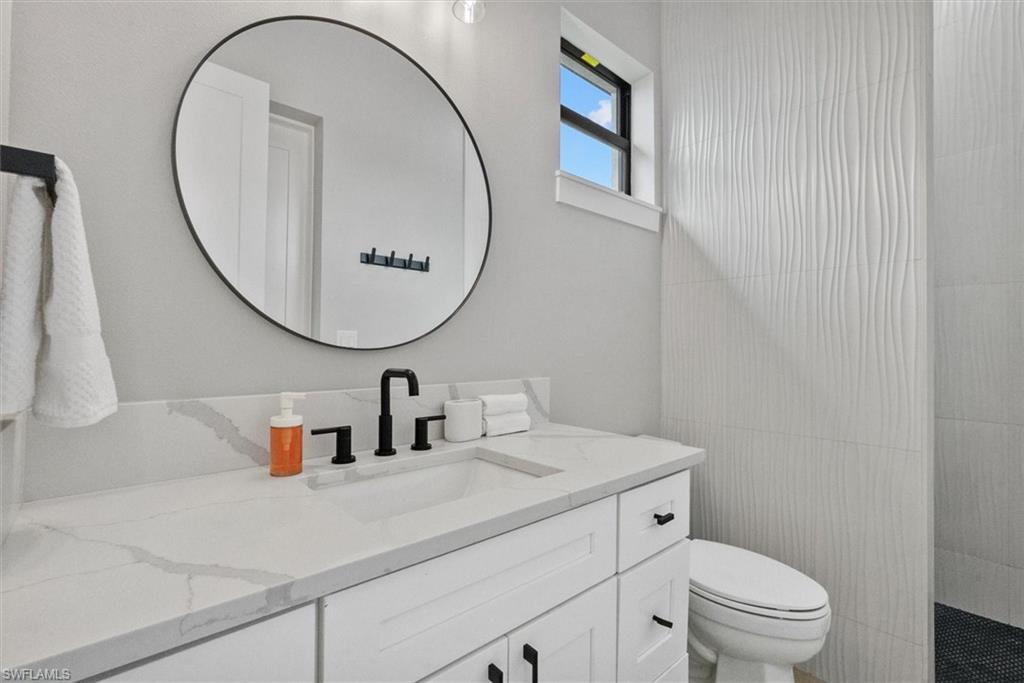 Full bath featuring vanity, a walk in shower, and tile walls