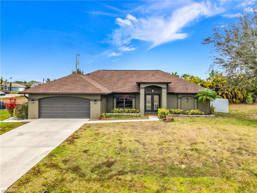 View of front facade with stucco siding, a front lawn, and concrete driveway