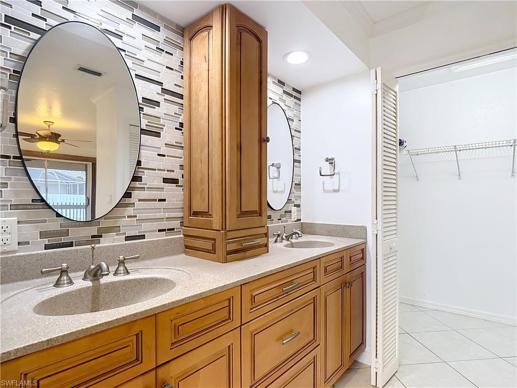 Full bathroom featuring double vanity, light tile patterned flooring, a walk in closet, and backsplash