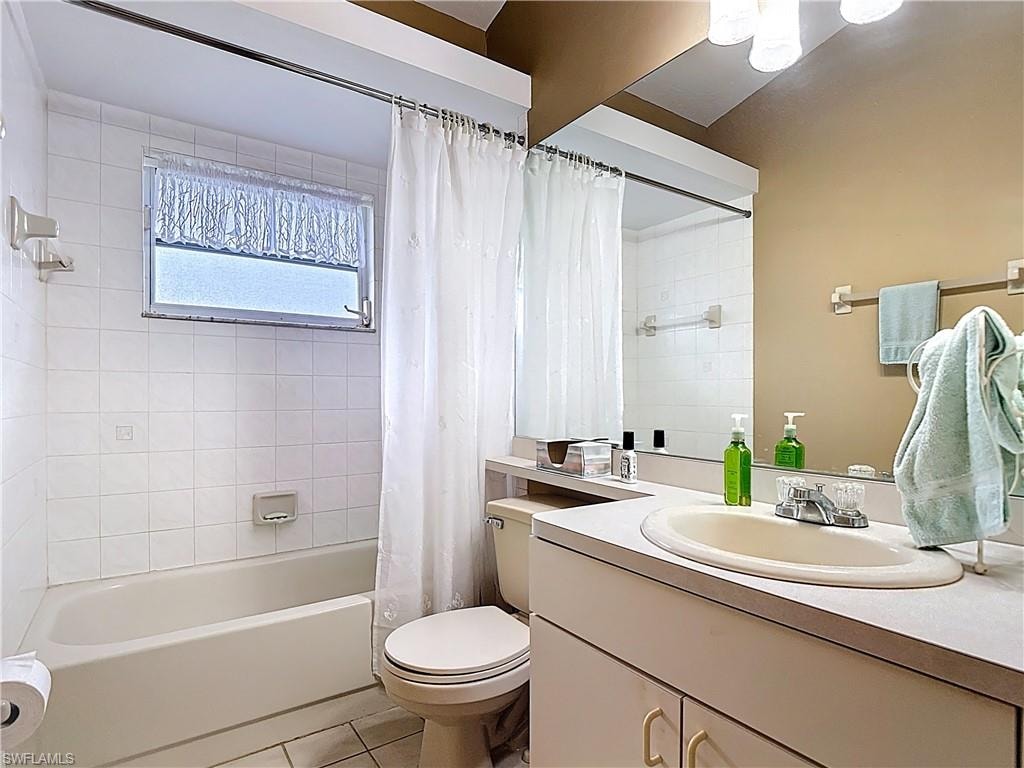 Full bath with vanity, light tile patterned floors, and shower / bathtub combination with curtain