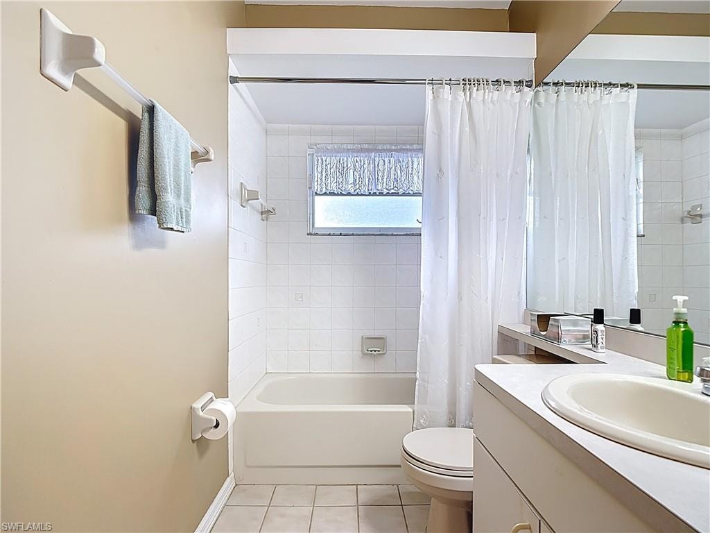 Bathroom featuring vanity, light tile patterned floors, and shower / bath combo with shower curtain
