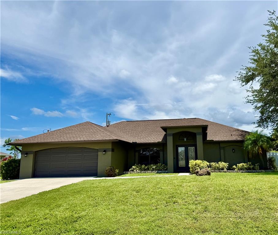 View of front facade with stucco siding, a front lawn, and concrete driveway