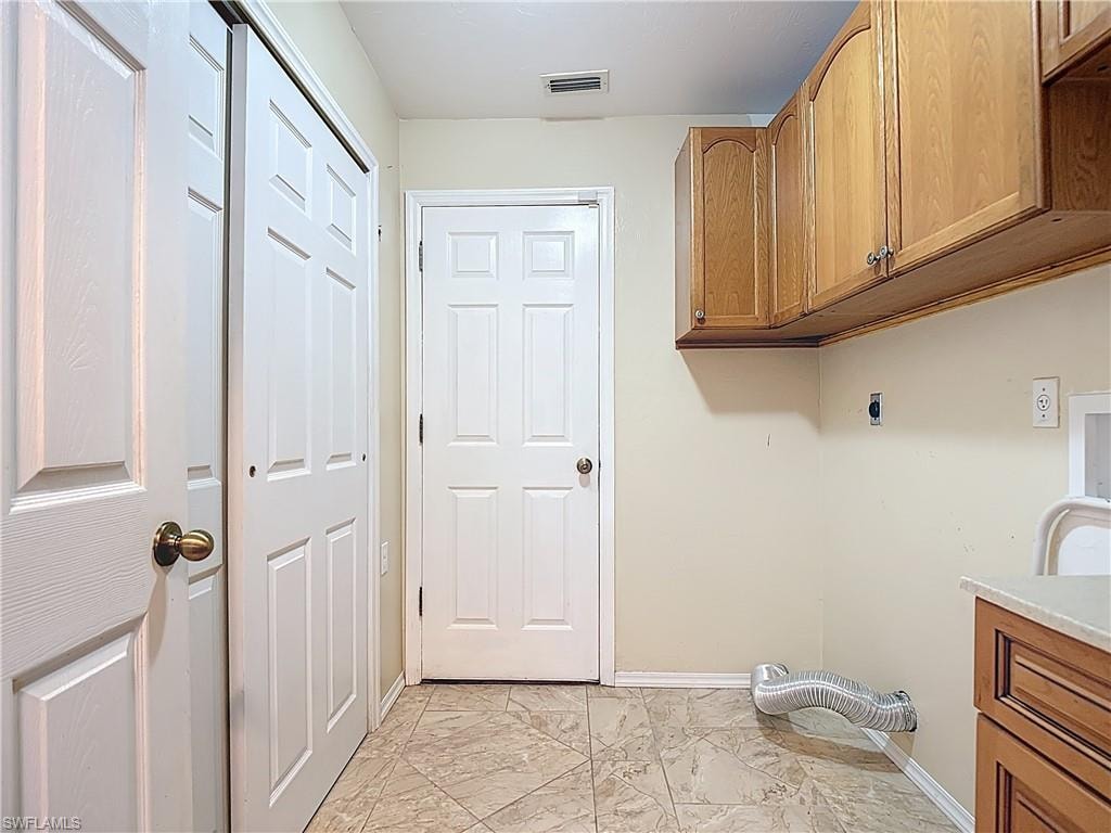 Laundry area with hookup for a washing machine, cabinet space, electric dryer hookup, and light marble finish flooring