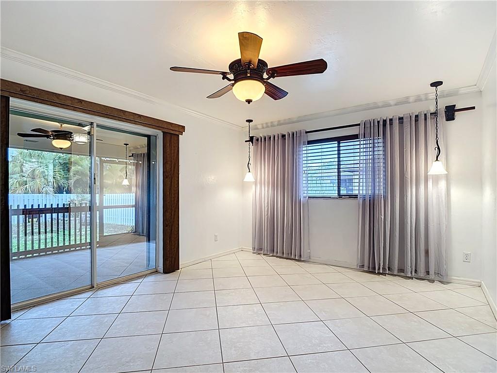 Empty room with a ceiling fan, ornamental molding, and light tile patterned floors