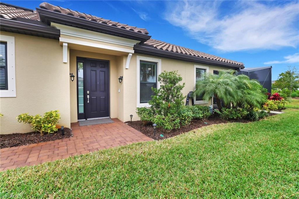 Entrance to property with stucco siding and a lawn
